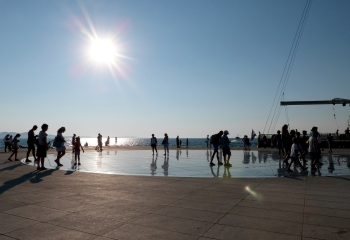 Mensen lopen in Zadar Kroatië bij zonsondergang over de boulevard